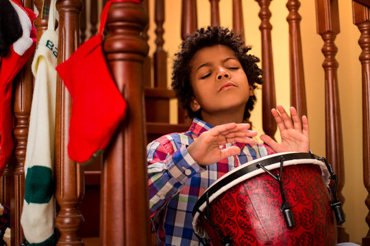 Enthusiastic darkskinned boy playing drum.