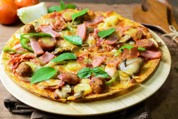 Rustic pizza with becon, salami, mozzarella and basil