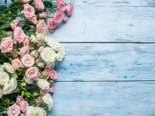 Delicate fresh roses on the blue wooden background.