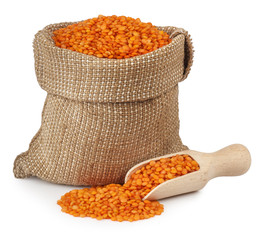 red lentils in burlap bag with wooden scoop on white