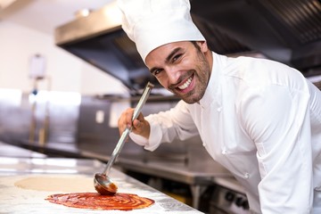Pizza chef put sauce on base