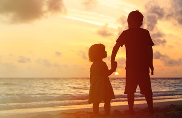 Fototapeta na wymiar little boy and girl holding hands at sunset