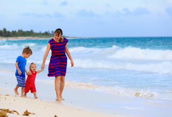 mother and two kids walking on the beach