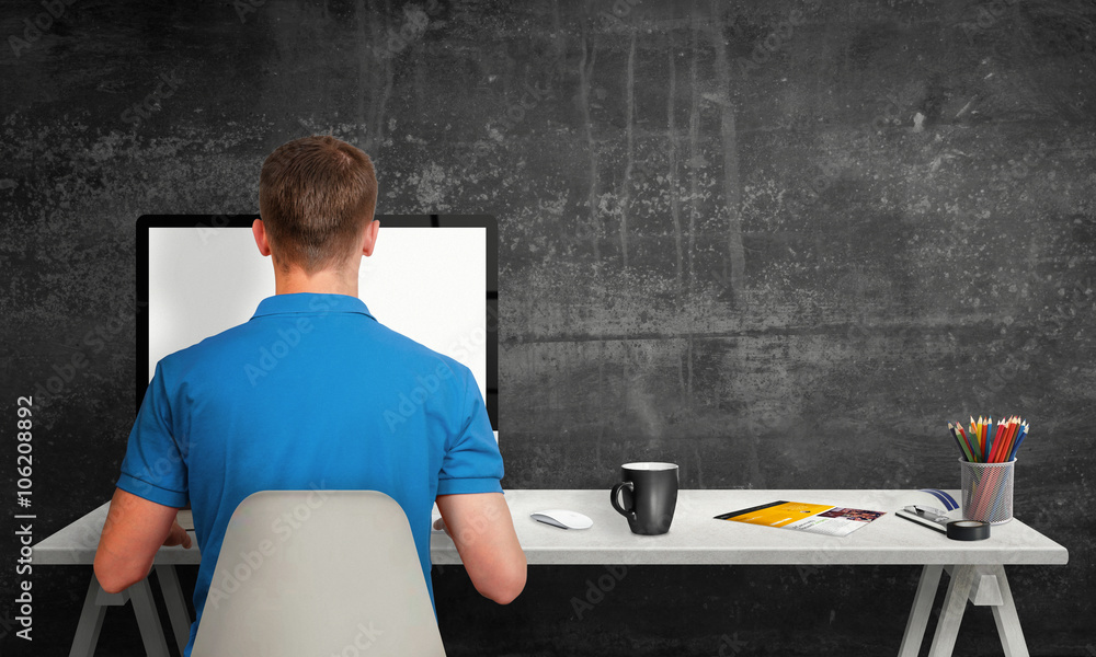 Poster man working on computer with isolated screen in office interior. work desk with keyboard, mouse, cup