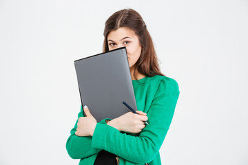 Cute lovely young woman in green jacket hiding behind folders