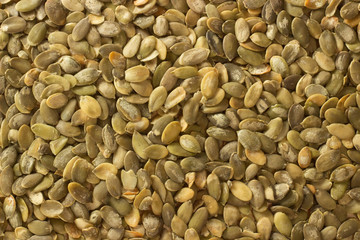 Macro background of pumpkin seeds and a wooden spoon