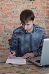 Fototapeta na wymiar Young man working in office, sitting at desk, writing