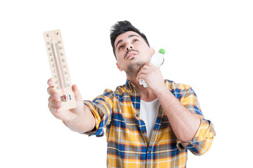 Concept of summer high temperature with man holding thermometer