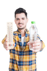 Handsome man holding a bottle of water and a thermometer