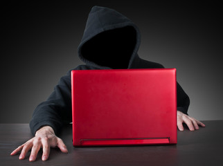 anonym hacker with hood and red laptop