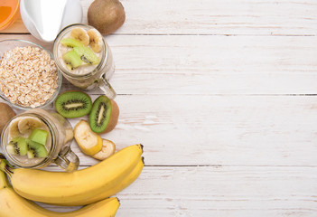 Smoothies with oatmeal, banana, kiwi in glass jars on a wooden background.