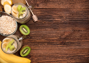 Smoothies with oatmeal, banana, kiwi in glass jars on a wooden background.Concept of cooking.  