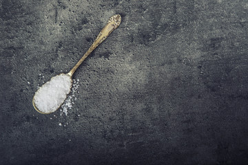 Salt. Coarse grained sea salt on granite - concrete  stone background with vintage spoon and wooden bowl.