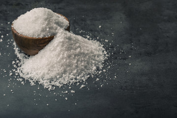 Salt. Coarse grained sea salt on granite - concrete  stone background with vintage spoon and wooden bowl.
