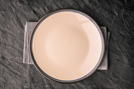 Ceramic plate on the dark stone table top view