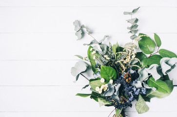 Bouquet of dried wild flowers on white table background with natural wood vintage planks wooden texture top view horizontal, empty space for publicity information or advertising text