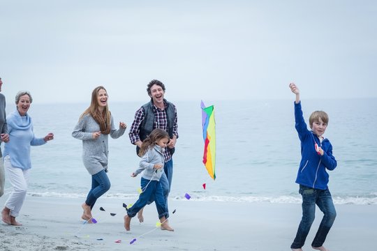 Cheerful multi-generation family running at sea shore
