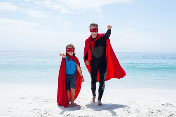 Cheerful father and son in superhero costume with hand raised