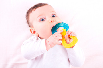 Baby girl with rattle teether toy.