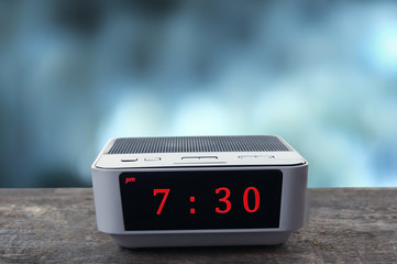 Digital clock showing 7:30 o'clock on wooden table, night background
