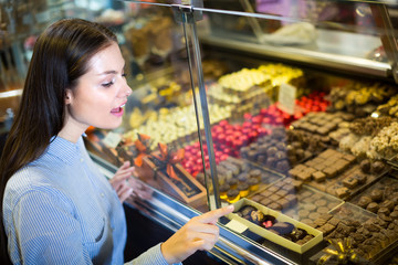 Smiling girl choosing chocolates.