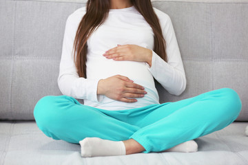 Pregnant woman sitting on sofa in the room