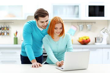 Young couple using laptop on the kitchen