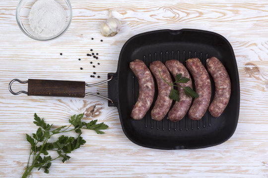 raw sausages on a  pan, salt and garlic, wooden background