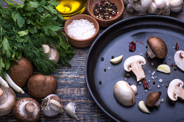 Fototapeta premium Mushrooms, parsley, dill, onion, olive oil, spices - ingredients for the preparation of mushroom dishes on the wooden background