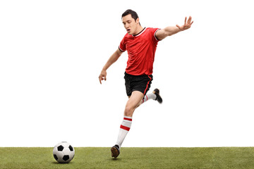Obraz premium Young football player kicking a ball