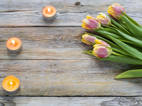 Tulips and candles on the wooden table