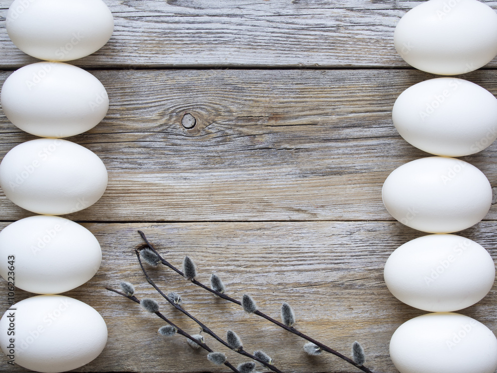 Wall mural Bunch of willow, white eggs and on wooden plank texture.