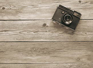 Retro film photo camera on the wooden background.