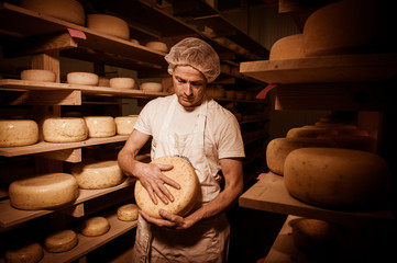 Cheese maker cleaning cheeses in his workshop