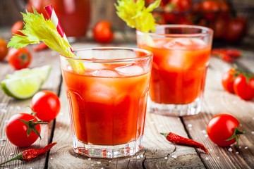 tomato juice with celery and ice in glasses