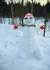Cheerful snowman stands alone in the near woods.