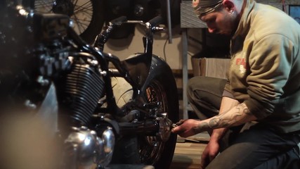 Auto mechanic assembles custom motorcycle in his workshop. Create an exclusive moto bike in the garage.
