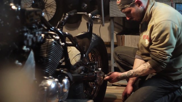 Auto mechanic assembles custom motorcycle in his workshop. Create an exclusive moto bike in the garage.