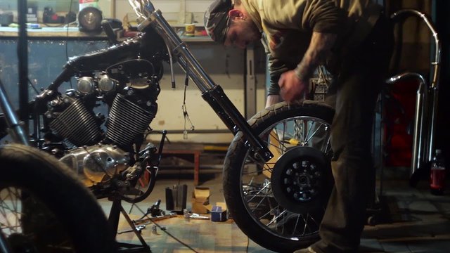 Auto mechanic assembles custom motorcycle in his workshop. Create an exclusive moto bike in the garage.