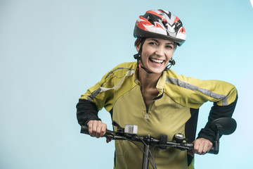 Donna vestita da ciclista ride sulla sua bici su sfondo celeste