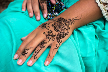Female hands with henna tattoo mehndi on bright blue dress