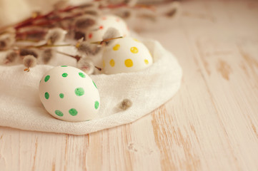 Easter eggs with spring branches of a willow on a wooden background.