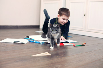 boy does homework on a floor and  kitten