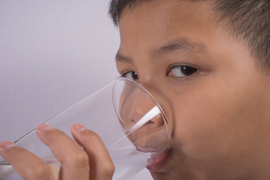 Young Asian boy drink water from a glass