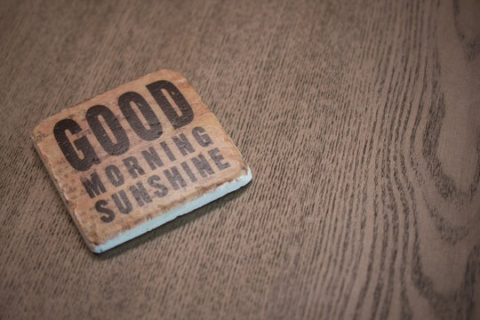 A Stone Coaster On A Wooden Table Surface Reading Good Morning Sunshine