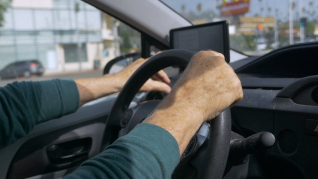 Hand held shot of a man driving and operating a GPS during the day