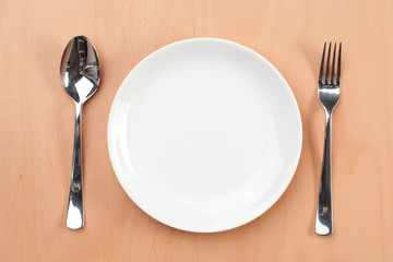 White empty plate with spoon and fork