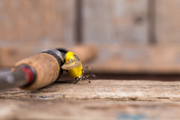 handle of fishing rod with lure on wooden