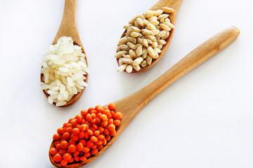 Rice, wheat and red lentil in wood spoon on white background