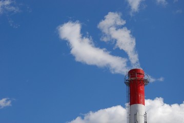 Heating plant with smoke like clouds on the clear blue sky